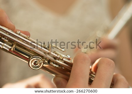 Detail of female fingers on flute keys with copy space and soft pastel background