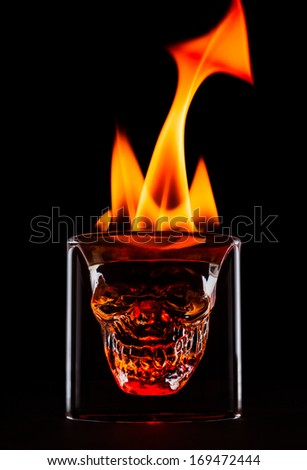 Skull shape glass with flames on the top. Single object on black background.
