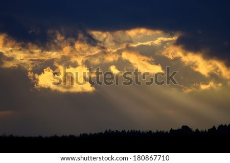 Golden sunset shining through dark clouds on canadian forest, Quebec, Canada