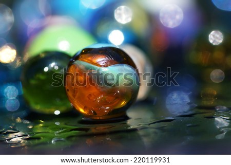 Artistic composition of multicolor group marbles, wet surface, reflection
