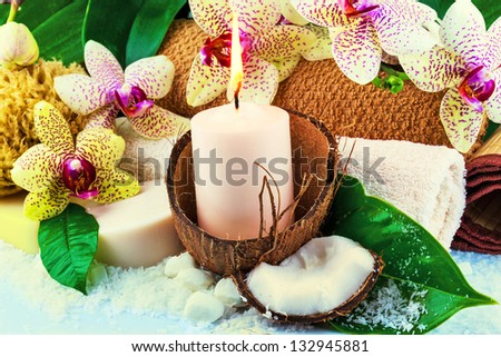 Spa concept with candle, coconut, orchid, towels, soap, green leaves