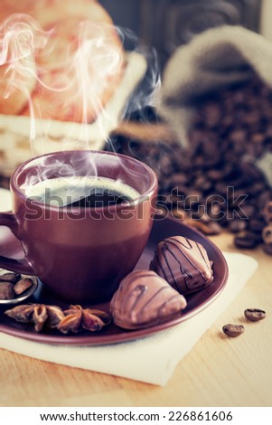 Cup of hot coffee with smoke steam and chocolate candies