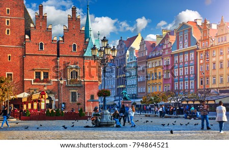 Wroclaw central market square with old colourful houses, street lamp and walking tourists people at evening sunset sunshine.