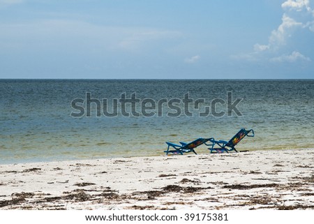 Two sunbeds by the water line on a beach