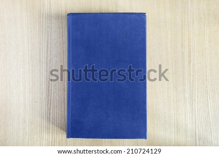 Book with blue blank cover on wooden table