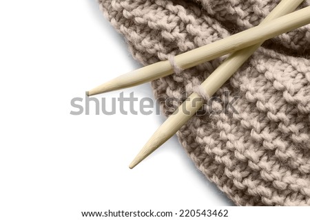 Wool knitting on wooden needles isolated over white as a background