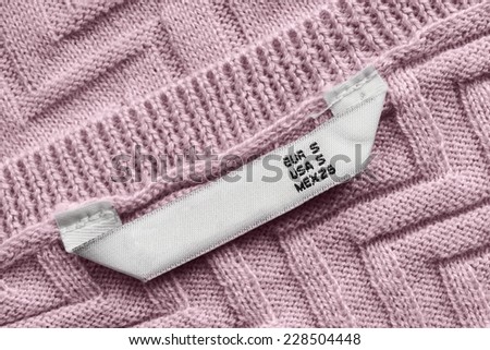 White size label on pink knitted cloth as a background