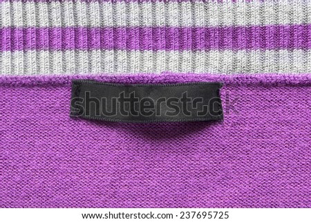 Black blank label on pink knitted cloth as a background
