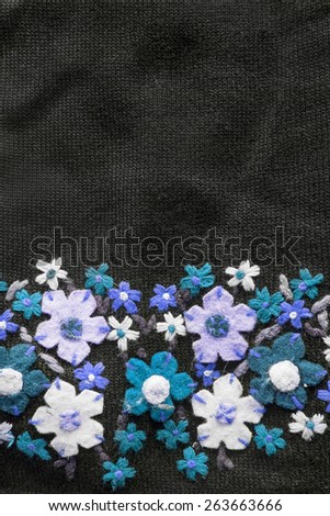 Black knitted cloth with felt blue flowers as a background