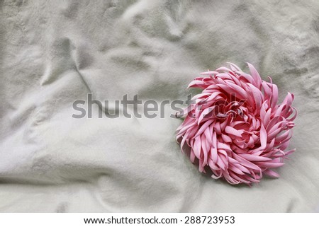 Pink flower brooch on crumpled linen as a background