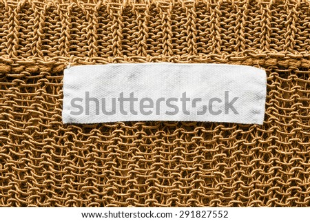 White blank label on golden knitted cloth as a background