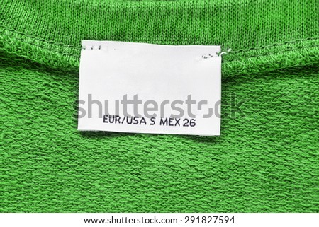 Blank clothes label on green material as a background