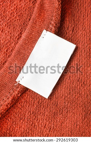 Blank white clothes label on terracotta cloth as a background