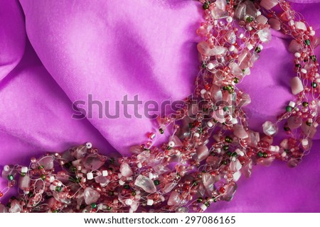 Pink glass beads on magenta silk as a background