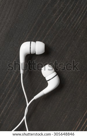 White wired earphones on wooden background