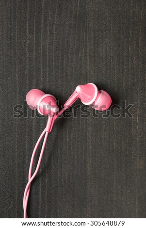 Pink wired earphones on wooden background