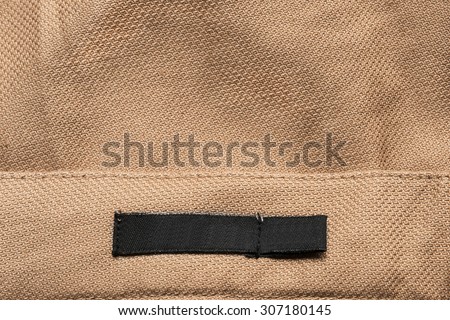 Black clothes label on beige cloth as a background