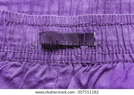 Blank clothes label on purple cotton as a background