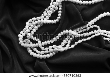 Pearl necklace on draped black silk as a background