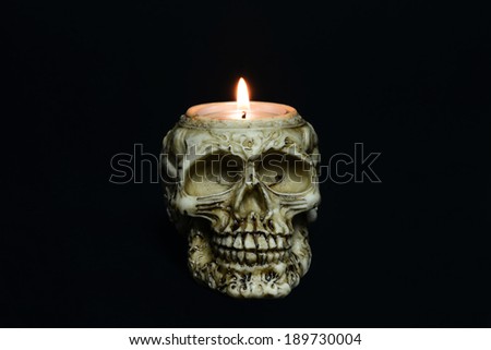 creepy skull candle on black background - front