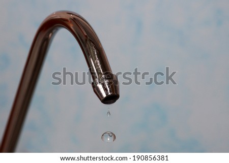 kitchen tap with water drops on a light-blue background