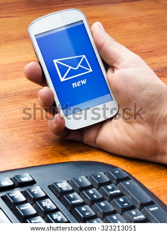 A man holding phone on the table with a new message at screen, selective focus