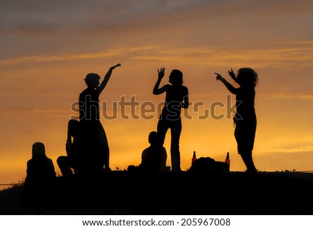 silhouette of friends partying at sunset