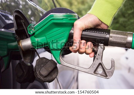 Female hand filling the car tank with gasoline