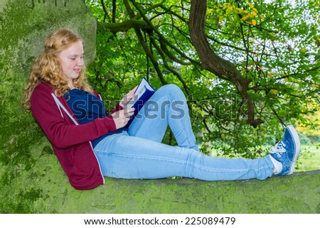 Girl lying on branch reading book in green tree in nature