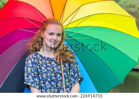 Teenage girl under colored umbrella outdoors