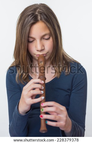 Teenage girl playing the flute isolated on white grey background