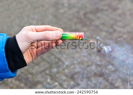 Hand holding colorful burning firework in street