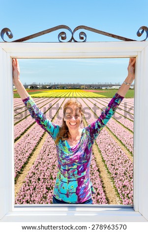 Woman standing in window in front of pink flowers field