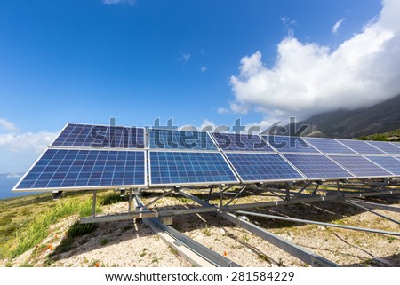 Row of solar collectors on mountain with blue sky and cloud