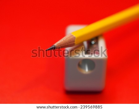 pencil/yellow pencil on sharpener with red background.