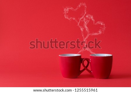 Cups of tea or coffee with steam in two heart shape on red background. Valentine\'s day celebration or love concept. Copy space