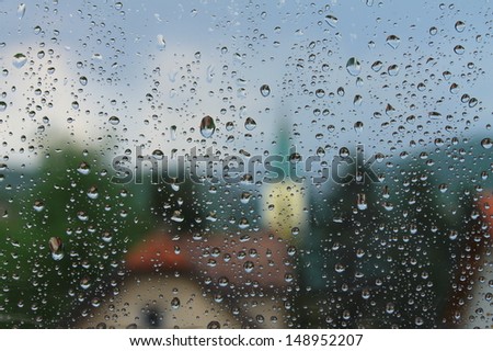 Rain drops on window with house and church on the background