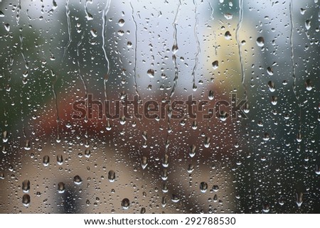 Rain drops on window with house and church in background , rainy day