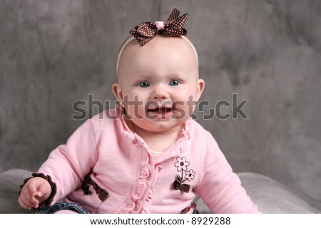 Beautiful Caucasian Baby Girl with Blue Eyes Smiling with a Bow in her hair