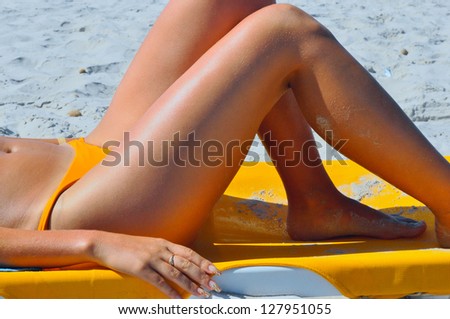 Girl sunbathing on the beach with beautiful legs