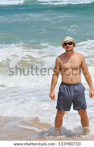 Man in shorts and sunglasses stands in water