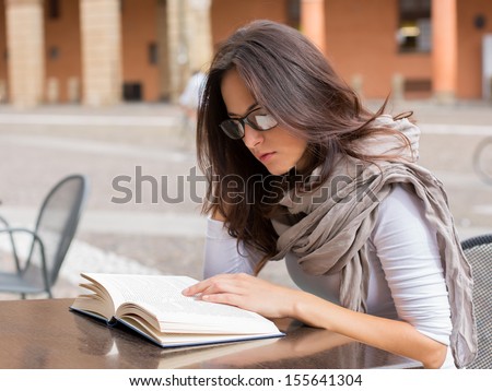 Beautiful girl reading a book on a spring day - outdoor portrait