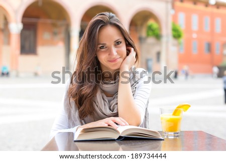 Beautiful girl smile and reading a book on a spring day - outdoor portrait
