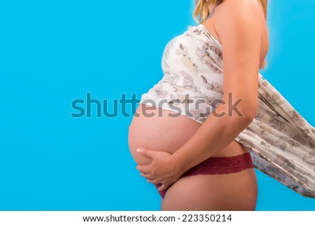Pregnant Woman Belly. Pregnancy Concept. Isolated on a Blue Background