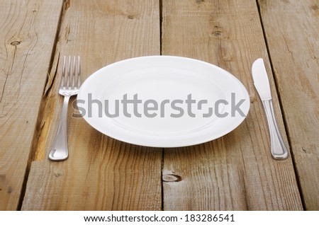 Empty plate, knife and fork on an old wooden table
