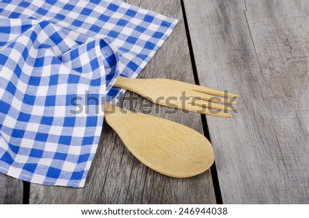 checkered napkin with wooden spoon and fork on old wooden table