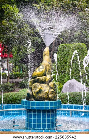Statue of golden seal sitting blow as fountain.