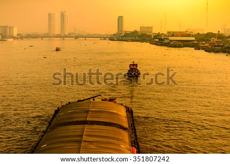 Boat pulled by a tugboat cargo carry the product at the Chaophaya river in Bangkok Thailand.