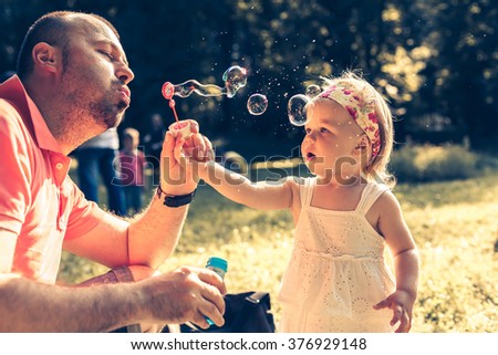 daddy and daughter blowing a bubbles in the park