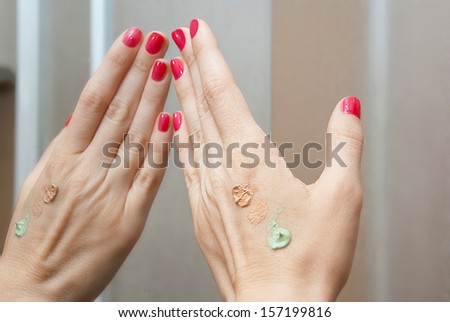 Try out different shades of beauty corrector on the hand in front of the mirror/Beauty corrector on hand